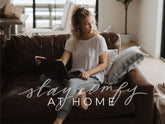 Woman using a laptop on a couch at home with overlaid text Stay comfy at home
