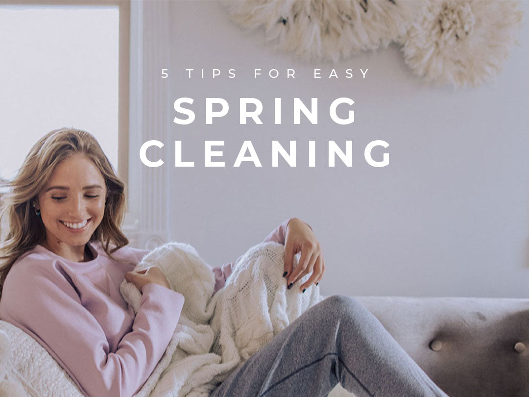 Woman folding a blanket on a sofa during spring cleaning