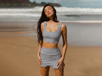 Woman posing in a houndstooth two-piece outfit on a beach