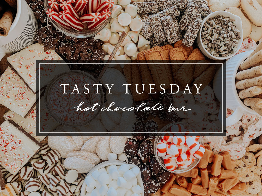Hot cocoa bar spread with marshmallows, peppermint candies, cookies, and chocolate treats