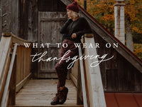 Woman poses in burgundy pants on a wooden bridge in autumn with overlay text What to wear on Thanksgiving