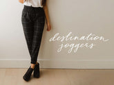 Front view of Destination Joggers showcasing a black windowpane pattern and wider ankle cuffs on a model indoors