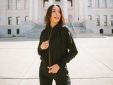 Model wearing a black zip-front jumpsuit outside a large neoclassical building