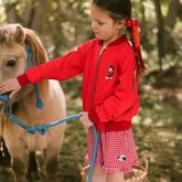 Child petting a pony while wearing a kid's Disney jacket in red with embroidered Mickey Mouse and kids Disney shorts in red gingham with embroidered Minnie Mouse.