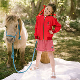 Young girl standing with a small pony and wearing a cute Disneyland outfit for kids—Mickey Mouse jacket for kids and Minnie Mouse shorts for kids.