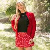 Woman in park wearing cute subtle Disney outfit—red women's Disney jacket, women's Disney tank top, and women's Disney tennis skirt.