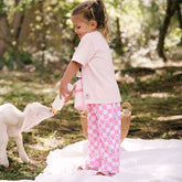 Child feeding a lamb outdoors wearing pink check Disney pants for kids