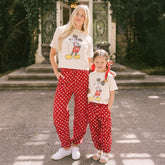 Woman and child wearing matching Disney outfits for families—Mickey tees and red polka dot Disney pants for women and kids.