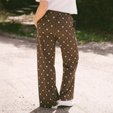 Close up back view of woman wearing brown polka dot pants that are perfect for Disneyland.