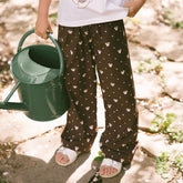 Close up of child in a garden wearing Minnie Mouse Disney pants for kids in brown with hidden Minnie print.