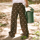 Close up back view of child wearing brown Minnie Mouse pants for kids Disney clothing holding a watering can in a garden.