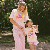 Woman and child wearing matching pink Disney Cinderella' t-shirts outdoors.