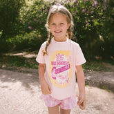 Young girl wearing a pink 'Cinderella' themed shirt and shorts outdoors.