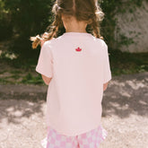 Back view of child wearing a pink shirt with an embroidered Cinderella crown on it.