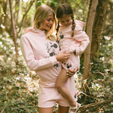 Woman and child wearing matching pink Disney outfits with Minnie Mouse design in a forest setting