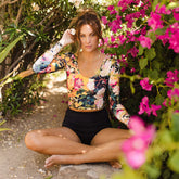 Model wearing long sleeve rash guard in floral print with high waist black bottoms