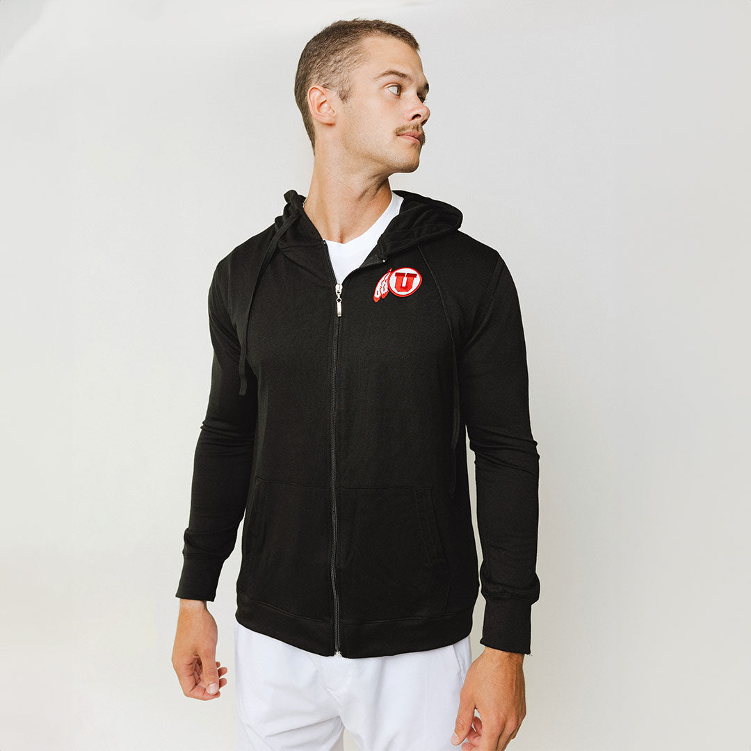 A man wearing a black zip-up hoodie with the University of Utah logo on the front.