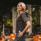 Three-quarter view of Perfect Jester Tee in vintage black showcasing short sleeves on a model with pumpkins in background