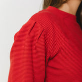 Close up of the Atlas Ribbed Sweater showing the texture of the crimson fabric