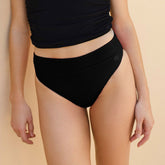 Close up front view of black high waisted bikini bottoms with high cut legs and thick waistband