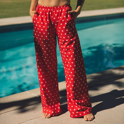 Woman standing by a pool wearing red wide-leg pants with white star pattern—the cutest matching outfit with swimsuit