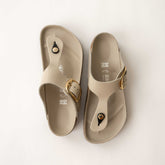 Pair of beige Birkenstock sandals with gold buckles on a white background
