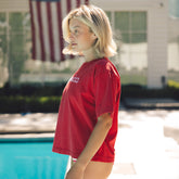 Person wearing a red shirt by a pool with an American flag in the background