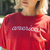 Close up of women's americana t shirt in red with embroidered america on front.