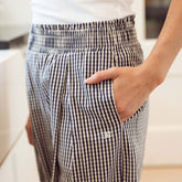 Close up of woman wearing navy gingham pants with hand in her pocket and visible Albion logo