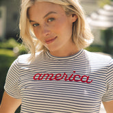 Woman wearing a striped shirt with 'america' printed on it outdoors.