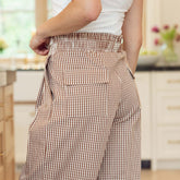 Close up of woman wearing brown gingham pants with back pockets in a kitchen setting