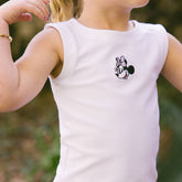 Child wearing a white sleeveless Minnie Mouse shirt for kids on blurred natural background