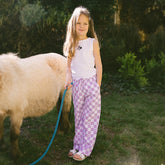Young girl standing next to a pony wearing a little girls Disneyland outfit—a Minnie tank top and Minnie pants for kids.