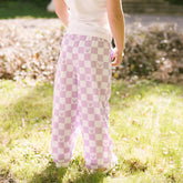 Back view of child standing in a garden wearing purple Minnie Mouse pants for kids