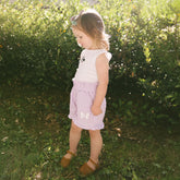 Young girl standing in a garden wearing a cute Minnie Mouse shirt and matching Disney shorts for kids.