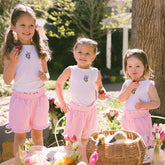 Three young girls in matching Disneyland outfits standing outdoors with a table and flowers in the background.