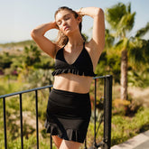 Model wearing black triangle bikini top with ruffle bottom