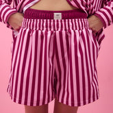 Person wearing pink striped women's shorts on a pink background