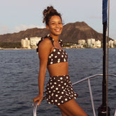 Woman in a polka dot swimsuit on a boat with Diamond Head in the background