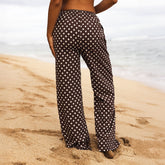 Person wearing polka dot pants standing on a sandy beach.