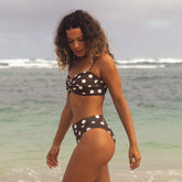 Woman in a polka dot bikini standing on a beach with ocean in the background
