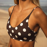 Woman wearing a brown bikini with white polka dots on a beach.