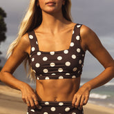 Woman wearing a brown polka dot bikini top on a beach