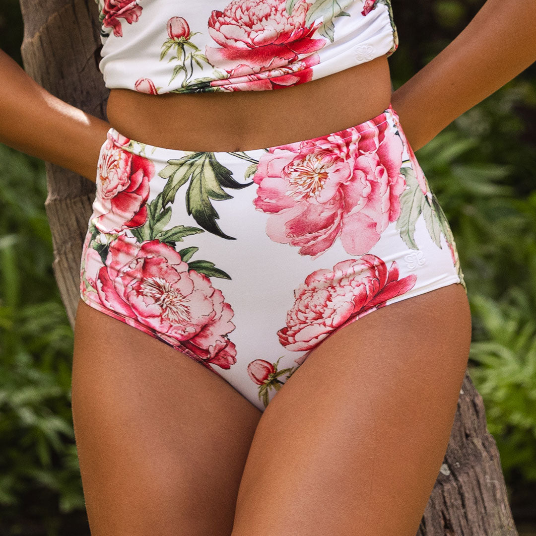 Floral high-waisted bikini with pink flowers on a white background, worn by a person.