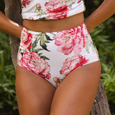 Floral high-waisted bikini with pink flowers on a white background, worn by a person.
