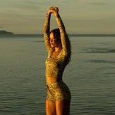 Woman on the beach at sunset wearing a women's two piece bathing suit