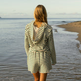 Woman wearing a striped hoodie and shorts standing on a beach