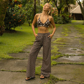 Woman in polka dot bikini top and pants standing on a stone path with greenery in the background