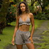 Woman wearing a striped triangle bikini top and trendy boxer shorts in a garden setting