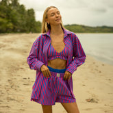 Woman wearing a pink and blue striped outfit on a beach